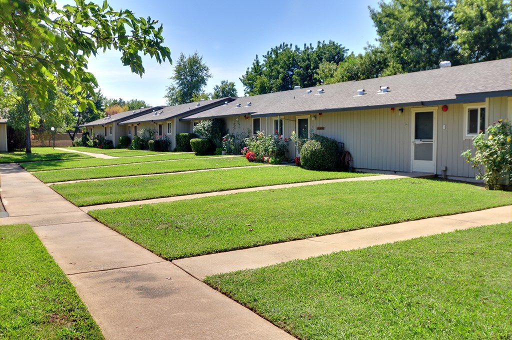 A row of houses with green lawns and trees in the background.