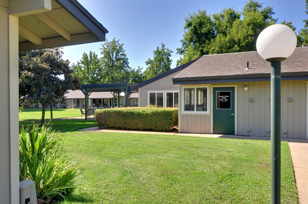 A small building with a green door is surrounded by a well-kept lawn.