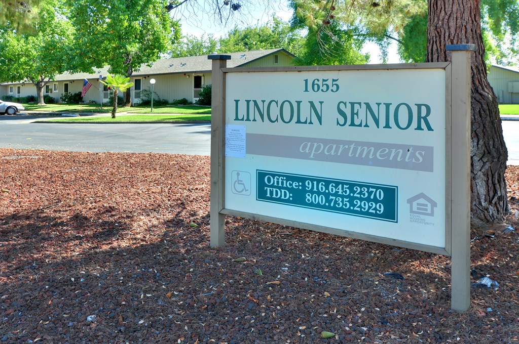 A sign for Lincoln Senior Apartments is displayed in front of a building.