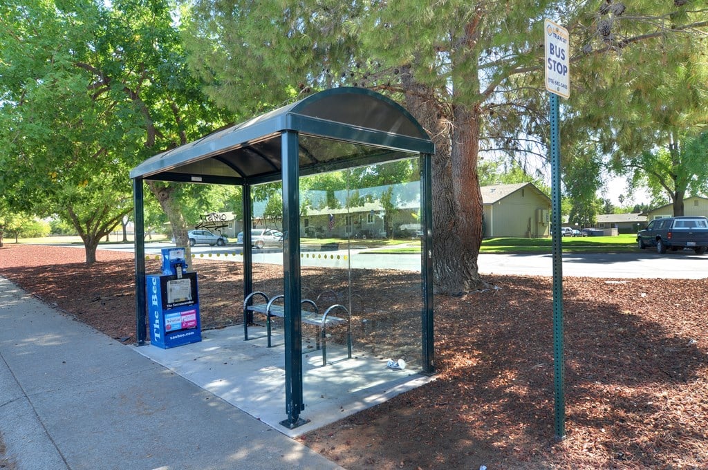 Bus stop with a bench and a trash can.