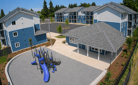 A playground area with a blue slide is surrounded by apartment buildings.