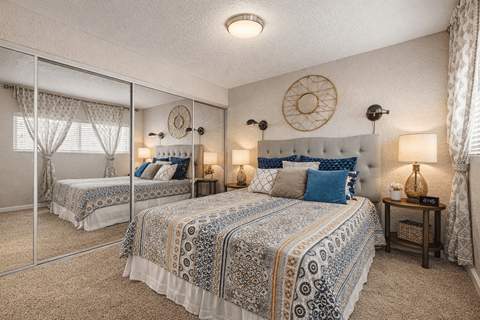 A bedroom with two beds and a mirror. at Infinity on the Landing Apartments , Texas