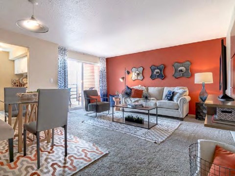 A living room with a grey sofa, a grey armchair, a glass coffee table and a rug.