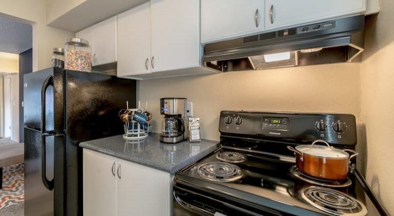 A black refrigerator and stove top oven in a kitchen at Infinity on the Landing Apartments, Euless, TX