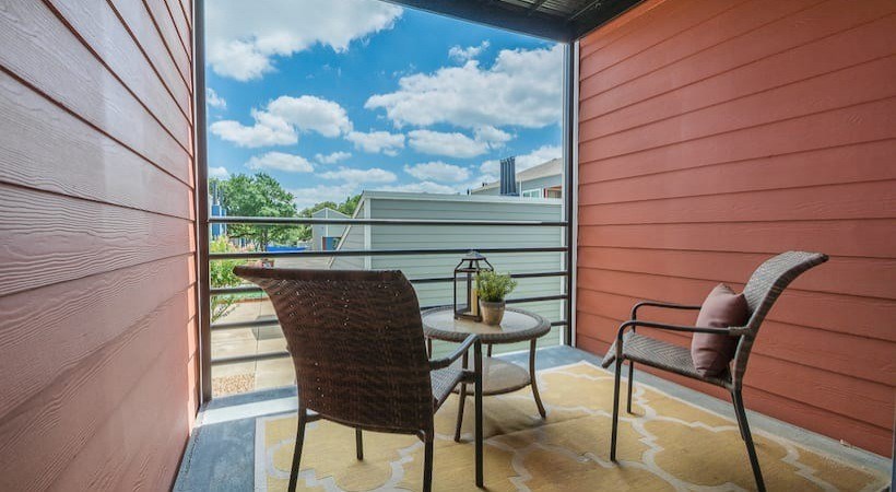A balcony with a chair and table overlooking a building at Infinity on the Landing Apartments, Texas, 76040