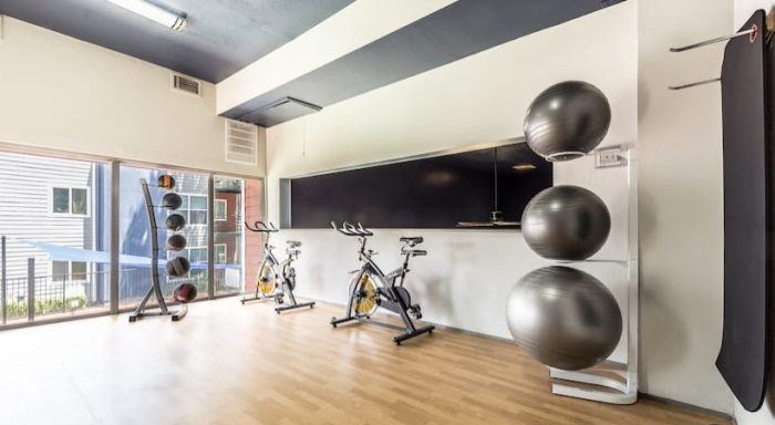 A gym with exercise equipment and a flat screen TV mounted on the wall at Infinity on the Landing Apartments, Euless, Texas