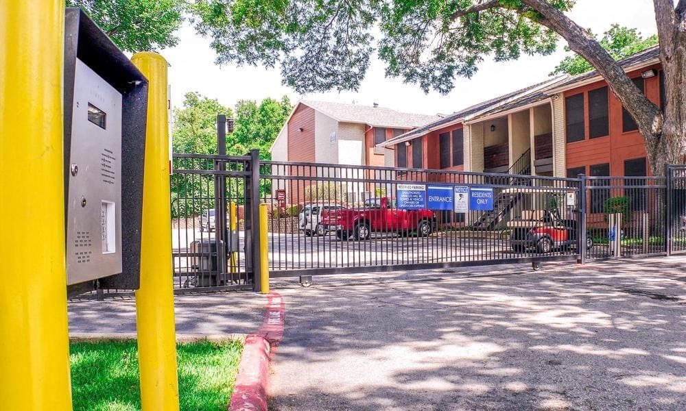 A yellow post box is on the left of a gate at Infinity on the Oaks Apartments, Dallas, TX, 75231