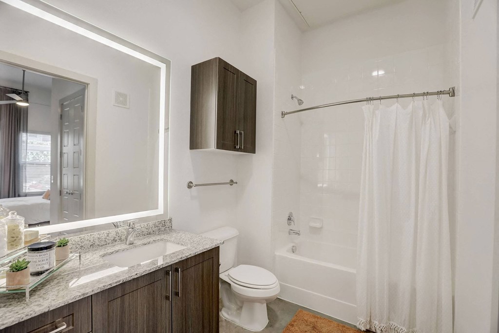 A white toilet sits next to a sink in a bathroom at Infinity on the Point Apartments, Dallas