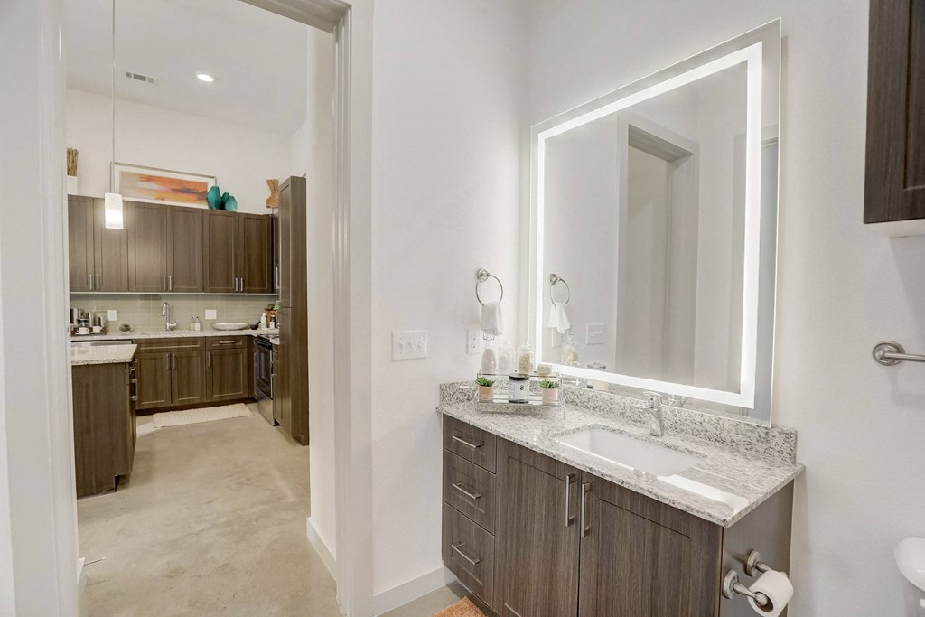 A bathroom with a sink, mirror, and cabinets at Infinity on the Point Apartments, Dallas 75243