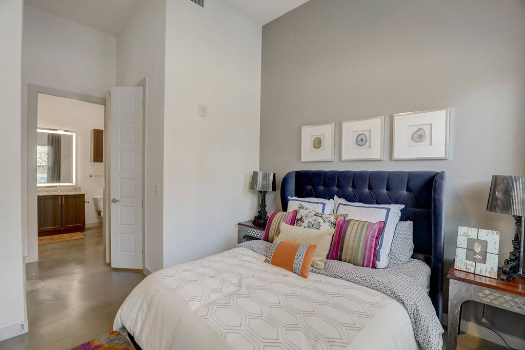 A bedroom with a large bed and a blue headboard at Infinity on the Point Apartments, Dallas, TX