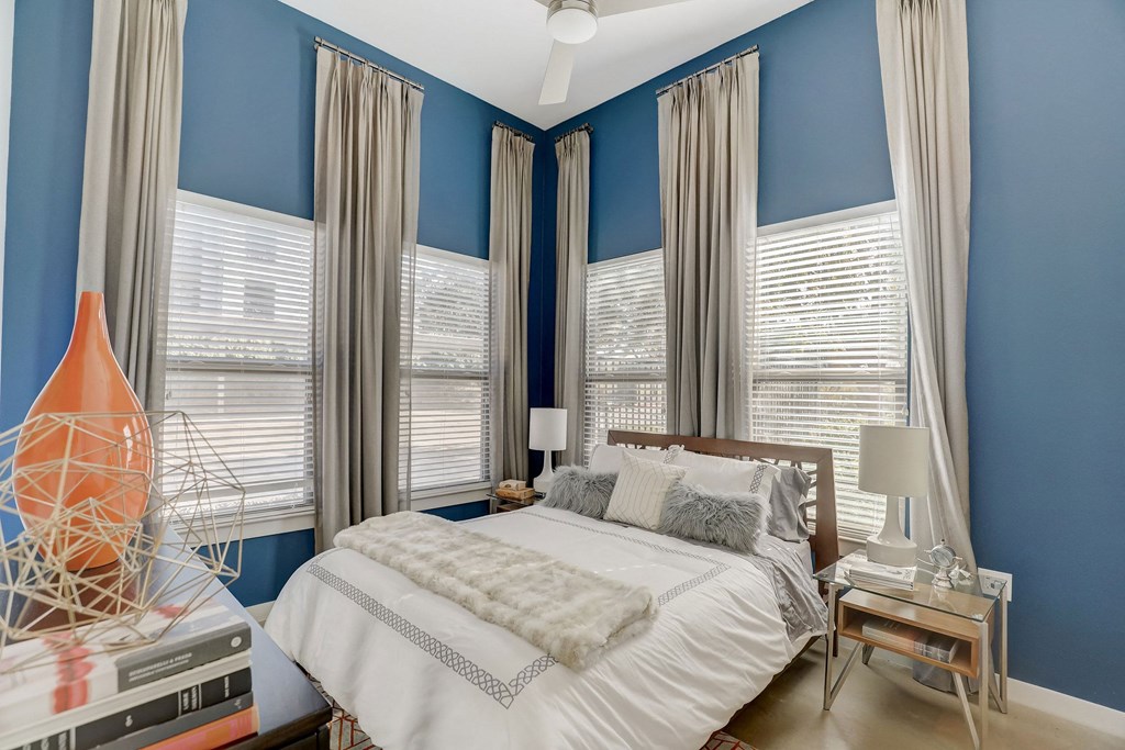 A bedroom with a bed, nightstand, and a vase on the side table at Infinity on the Point Apartments, Texas