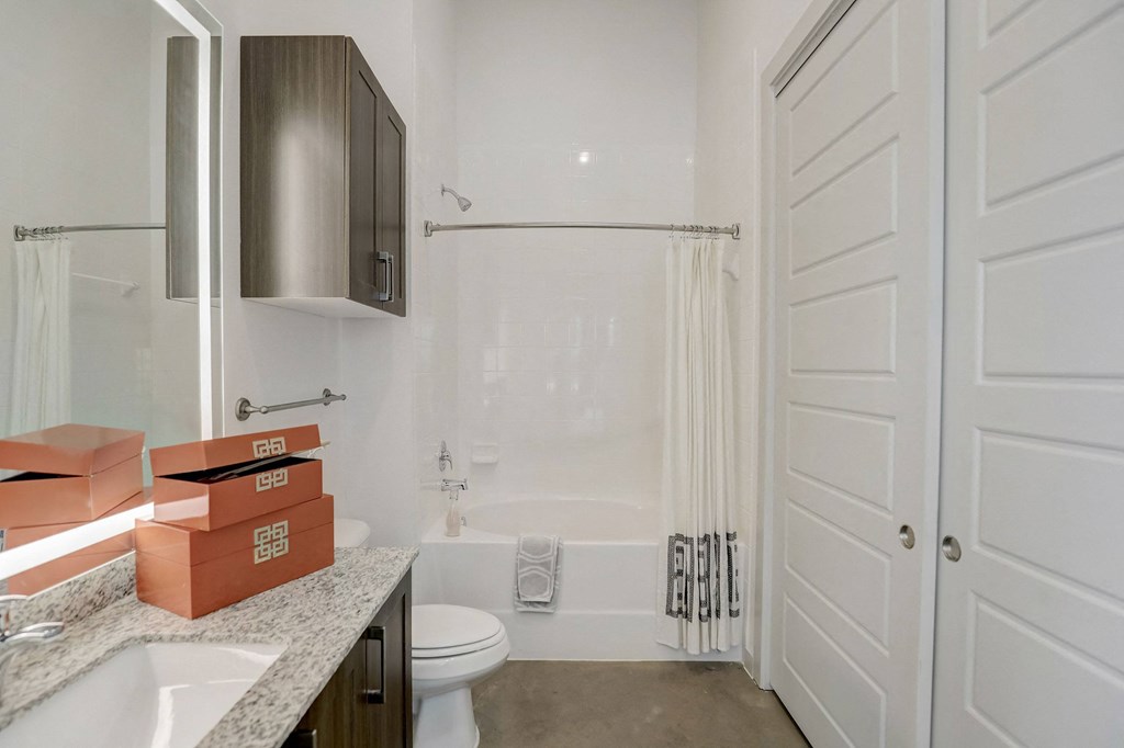 A bathroom with a toilet, sink, and shower at Infinity on the Point Apartments, Dallas 75243