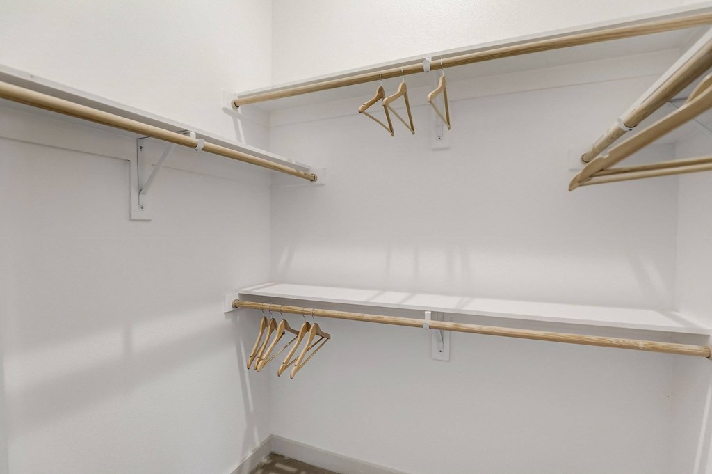 A white closet with two shelves and hangers at Infinity on the Point Apartments, Texas