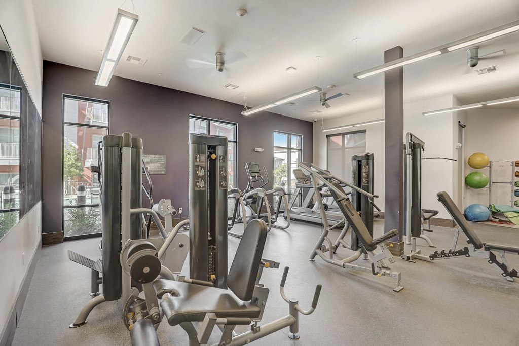A gym with a variety of equipment including weights and exercise balls at Infinity on the Point Apartments, Texas, 75243