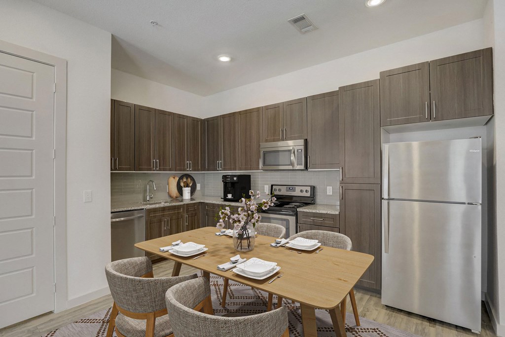 A modern kitchen with a dining table set for two at Infinity on the Point Apartments, Texas