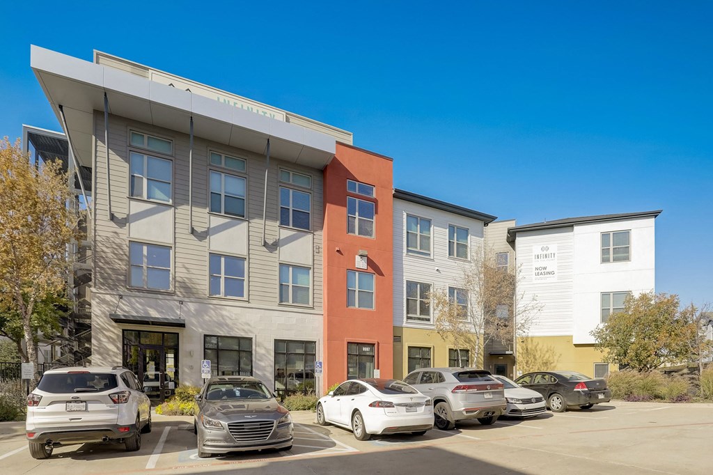 A modern building with a parking lot in front of it at Infinity on the Point Apartments, Dallas 75243