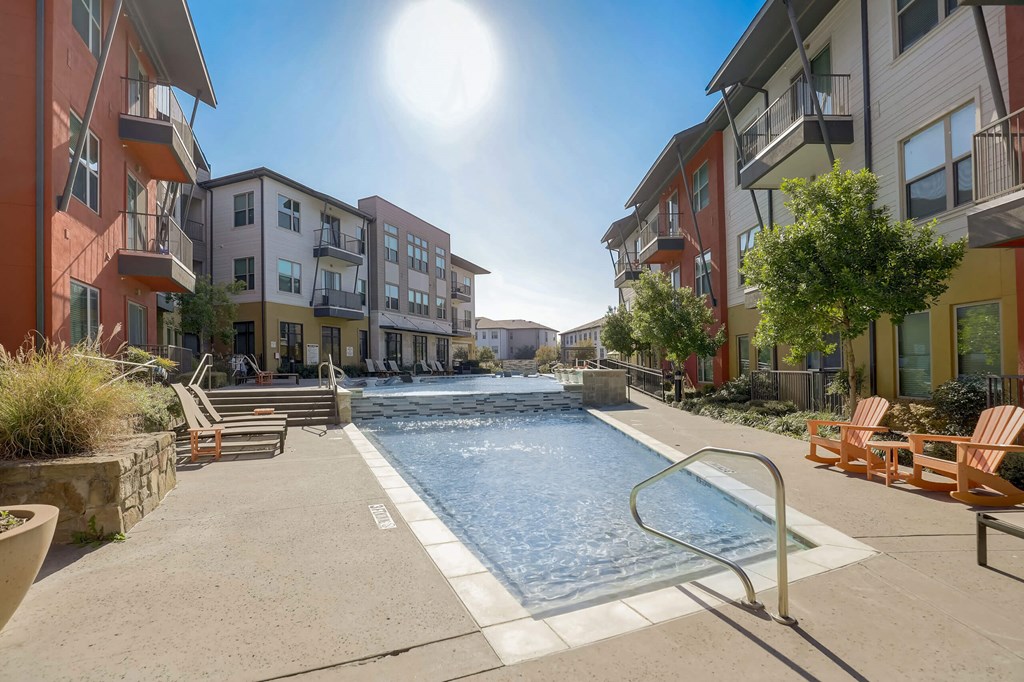 A sunny day at a pool surrounded by apartment buildings at Infinity on the Point Apartments, Texas, 75243