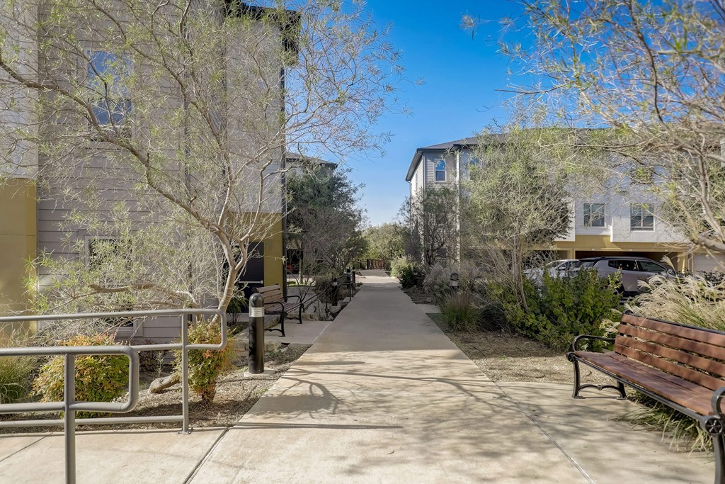 A sunny day in a residential area with a sidewalk and benches at Infinity on the Point Apartments, Texas, 75243