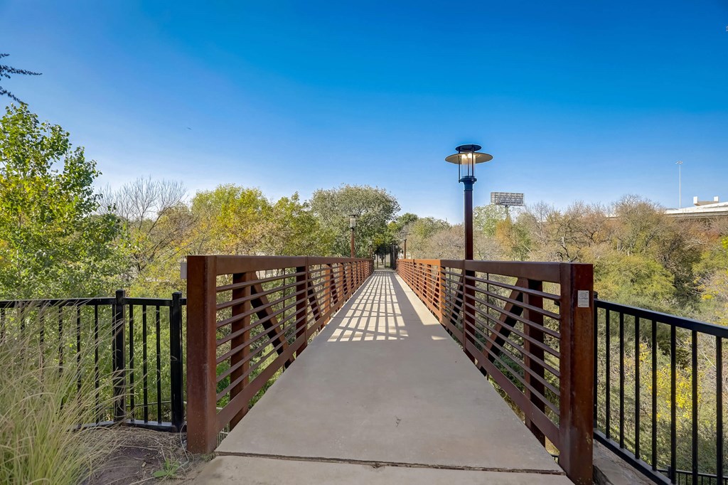 A bridge with a metal railing and a light post on top at Infinity on the Point Apartments, Dallas