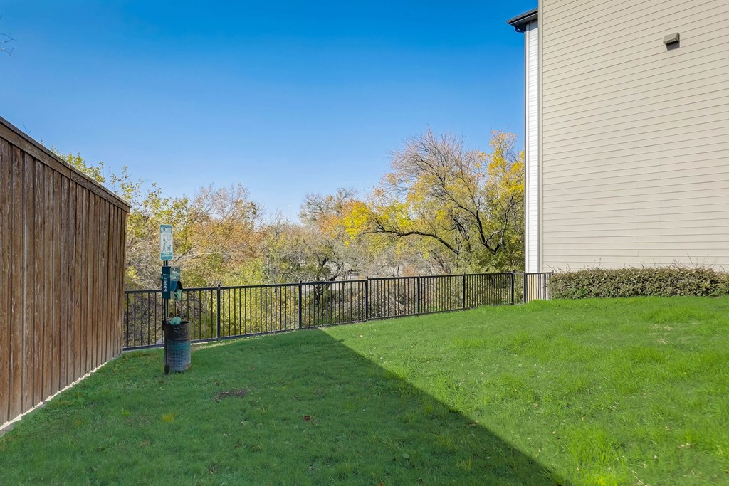 A backyard with a wooden fence and a green lawn at Infinity on the Point Apartments, Texas