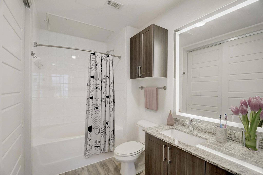 A white bathroom with a shower, toilet, and sink at Infinity on the Point Apartments, Dallas, TX, 75243