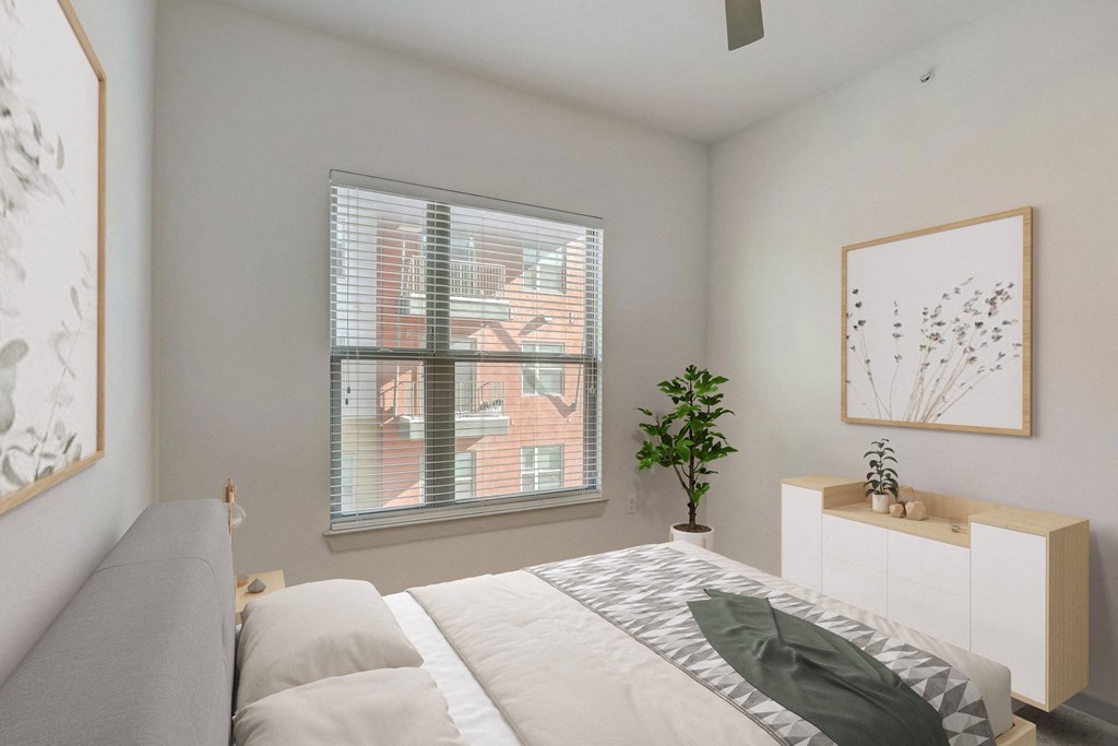 A bedroom with a bed, a plant, and a framed picture on the wall at Infinity on the Point Apartments, Dallas, TX