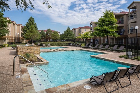 A swimming pool surrounded by chairs and trees at Infinity on Sunnyvale Apartments , Mesquite, 75150