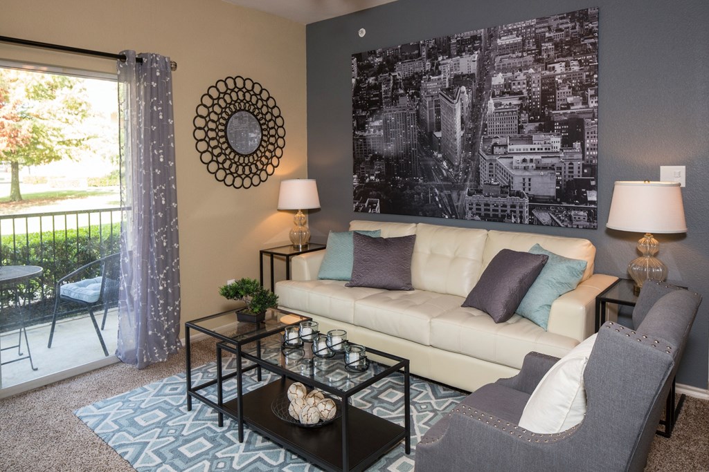 A living room with a couch, chair, and a large picture on the wall.