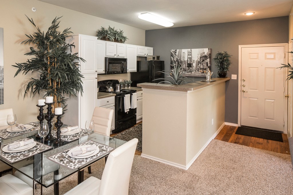 A modern kitchen with a glass table set for two.