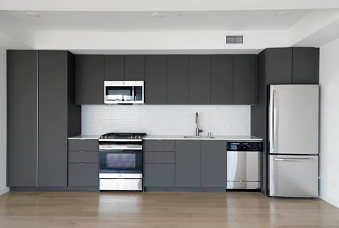 A modern kitchen with a stainless steel refrigerator and oven.