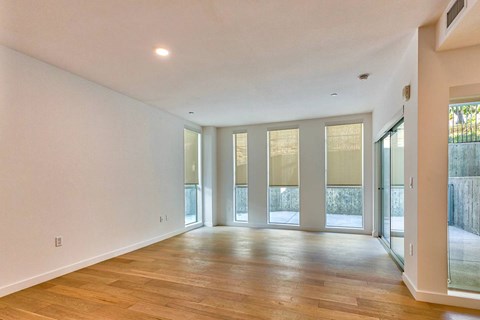 A spacious room with wooden floors and large windows.