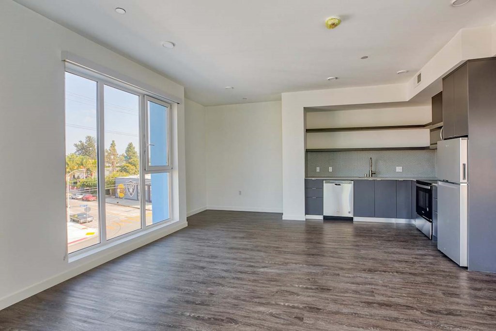 A spacious kitchen with a refrigerator, cabinets, and a countertop.at Catalina West Adams, Los Angeles California