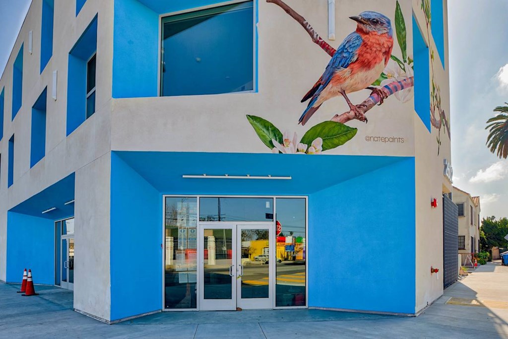 A blue building with a mural of a bird on it.at Catalina West Adams, Los Angeles, 90016