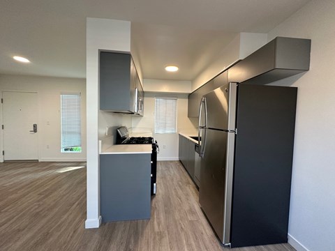 A kitchen with a black refrigerator and a grey island.