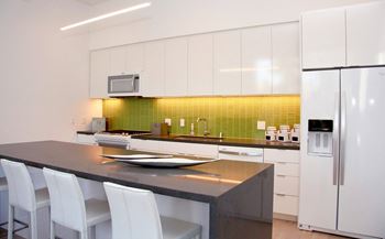 A modern kitchen with white cabinets and a black countertop. at The Geffen, California