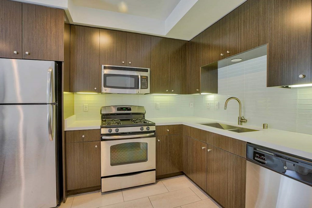 A modern kitchen with a stainless steel refrigerator, microwave, oven, and sink.at 1800 Whitley, Los Angeles California