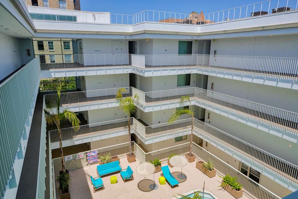 A balcony with a table and chairs overlooks a courtyard.at 1800 Whitley, Los Angeles California
