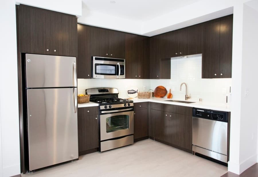 A modern kitchen with dark wood cabinets and stainless steel appliances.at 1800 Whitley, Los Angeles, 90028