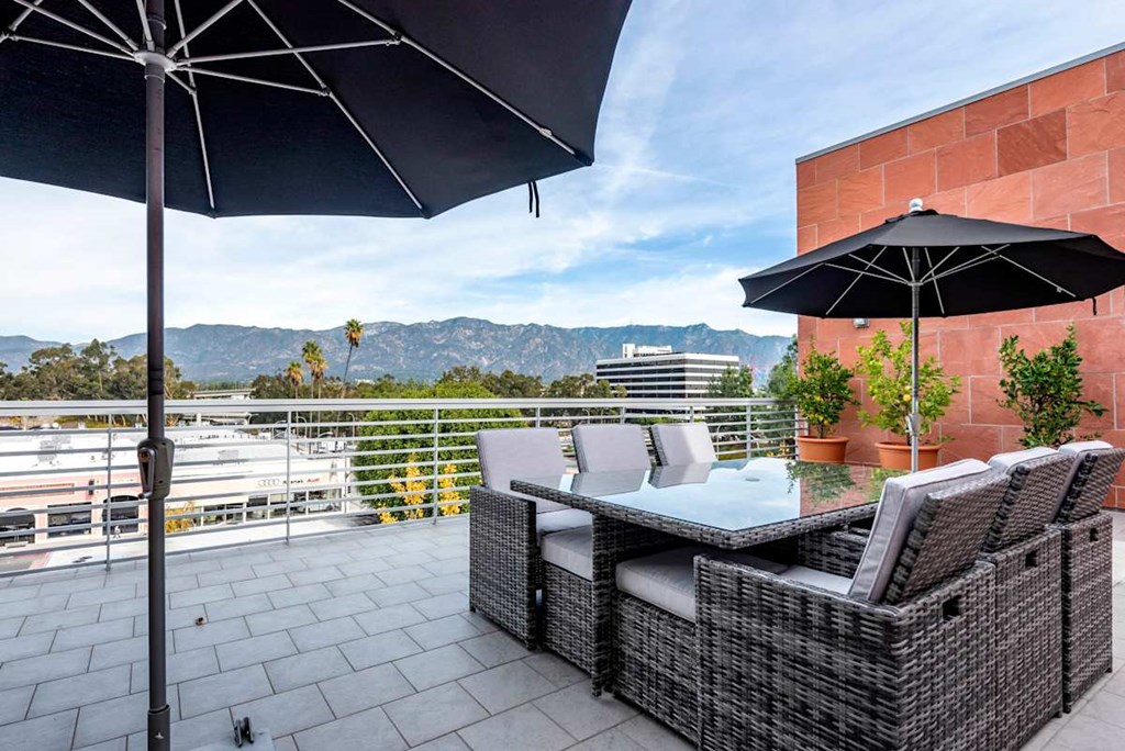 A patio with a table and chairs under umbrellas.at Catania, Pasadena, 91105