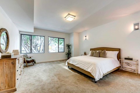 A bedroom with a large bed, a wooden dresser, and a mirror on the wall.
