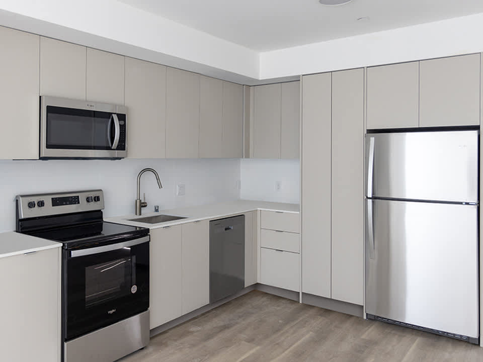 A modern kitchen with a stainless steel refrigerator, oven, and microwave.