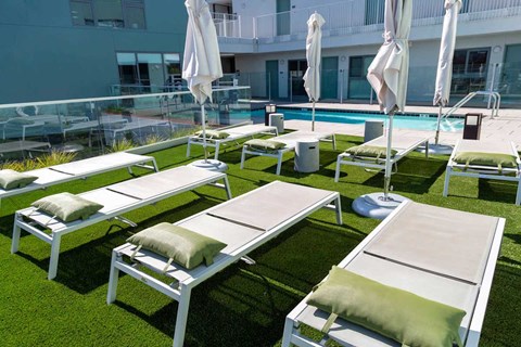 A sunny day at the pool with white sun loungers and umbrellas.