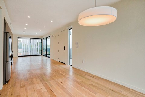 A spacious room with wooden floors and a large window.