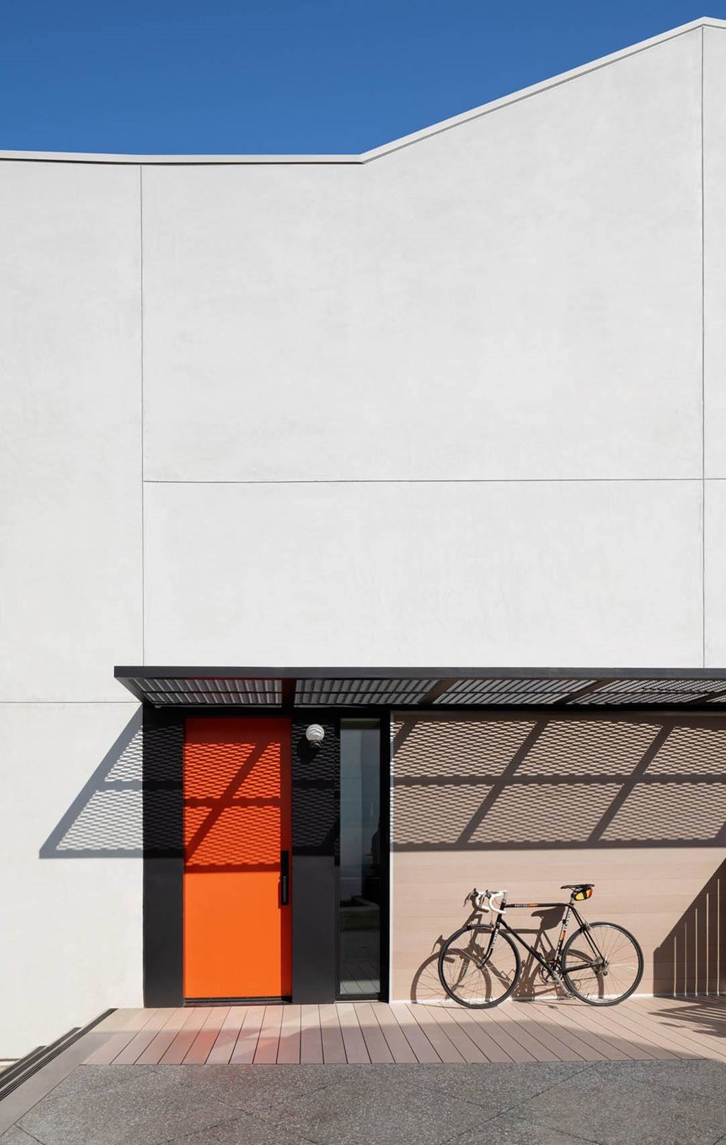 A bicycle is parked in front of a building with a red door.at 810 Ashland, Santa Monica, 90405