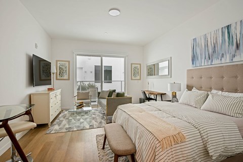 A bedroom with a large bed and a television on the wall.