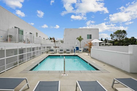 A pool with lounge chairs and a white building in the background.