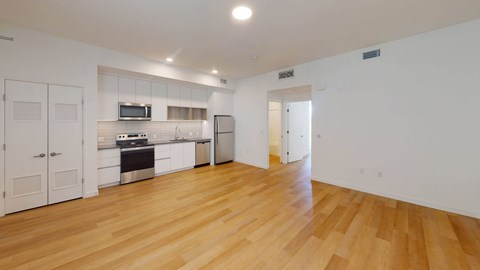 A kitchen with white cabinets and a wooden floor.