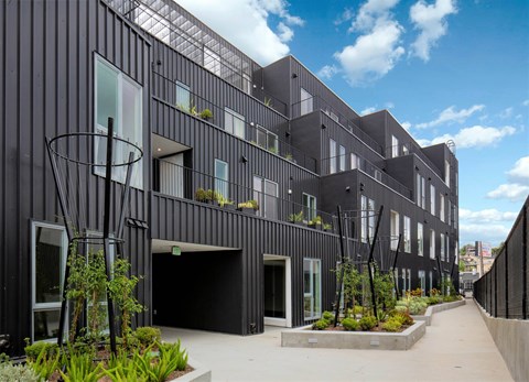 A modern black building with a courtyard in front.