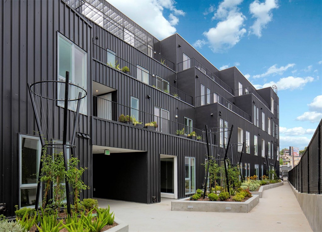 A modern black building with a courtyard in front.