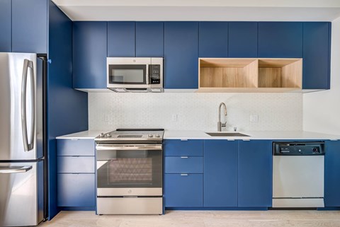 A kitchen with blue cabinets and a stainless steel refrigerator.